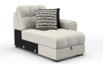Light beige fabric chaise lounge with tufted cushions, right armrest, and two decorative pillows in black and patterned gray.