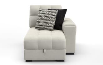 Light beige fabric chaise lounge with tufted cushions, right armrest, and two decorative pillows in black and patterned gray.