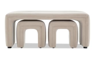 Beige upholstered nesting stools set featuring a large rectangular bench with two smaller arched stools underneath, designed for modern living spaces.