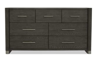 Dark gray wooden dresser with six drawers, sleek silver handles, modern design, and metal-capped legs, suitable for bedroom storage.
