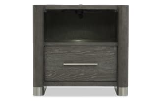 Dark gray wooden nightstand with rounded corners, a single drawer with a horizontal metal handle, open shelf above, and metal feet.