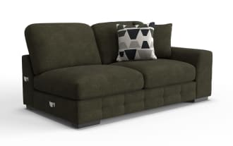 Dark olive green fabric loveseat sofa with thick cushions, wide armrest on the right, and two decorative pillows including one with geometric patterns.