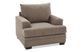 Brown upholstered fabric armchair with plush cushions, wide seat, and low wooden block legs, designed for living room comfort.