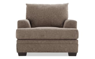 Brown upholstered fabric armchair with plush cushions, wide seat, and low wooden block legs, designed for living room comfort.