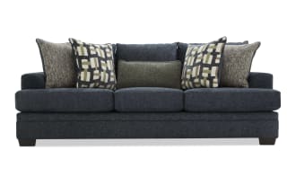 Dark blue fabric sofa with three seat cushions and six decorative pillows in geometric and textured patterns, modern living room furniture.