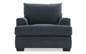 Dark gray upholstered armchair with plush cushions, wide seat, and wooden block legs, designed for comfortable living room seating.
