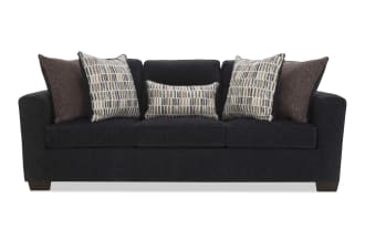 Dark gray fabric sofa with three seat cushions and five decorative pillows in brown and patterned beige, ideal for modern living rooms.