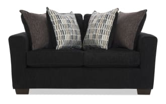 Black fabric loveseat sofa with wide arms, wooden block legs, and four decorative pillows in brown and patterned beige tones, modern style.