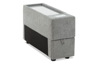 Gray fabric-covered rectangular storage ottoman with a pull tab and black cylindrical legs, designed for living room organization and seating.