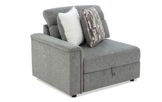 Gray fabric sectional sofa corner piece with two decorative pillows, featuring a cushioned armrest and tufted backrest for modern living room seating.