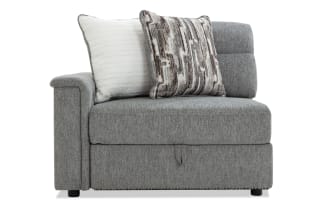 Gray fabric sectional sofa corner piece with two decorative pillows, featuring a cushioned armrest and tufted backrest for modern living room seating.