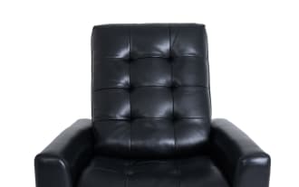 Black leather recliner chair with tufted backrest and padded armrests, designed for comfortable seating and relaxation.