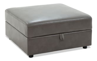 Gray leather storage ottoman with cushioned top, rectangular shape, and short black legs, designed for seating and hidden storage.