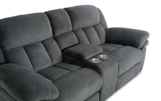 Dark gray plush fabric reclining loveseat with padded armrests, high back cushions, and a center console with cup holders, designed for comfort and relaxation.