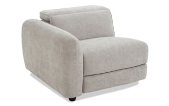 Modern gray fabric armchair with rounded left armrest, cushioned seat and backrest, and black wooden legs, ideal for living room seating.