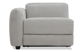 Modern gray fabric armchair with rounded left armrest, cushioned seat and backrest, and black wooden legs, ideal for living room seating.