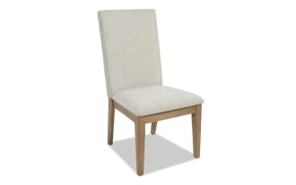 Upholstered dining chair with beige fabric seat and backrest, solid wood frame in natural finish, modern minimalist design.