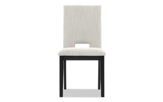 Upholstered dining chair with beige fabric seat and backrest, black wooden legs, and a rectangular cutout at the lower back.