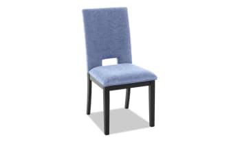 Modern dining chair with light blue upholstered fabric seat and backrest, featuring a small rectangular cutout and black wooden legs.