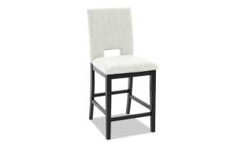 Upholstered dining chair with light gray fabric seat and backrest, black wooden legs, and a rectangular cutout in the backrest.