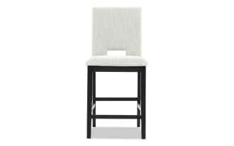Upholstered dining chair with light gray fabric seat and backrest, black wooden legs, and a rectangular cutout in the backrest.