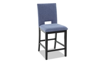 Upholstered bar stool with blue fabric seat and backrest, black wooden legs, and a rectangular cutout in the backrest for modern dining or kitchen use.