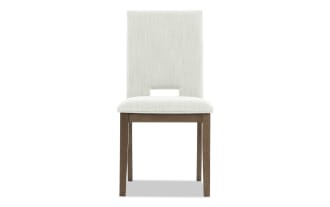 Upholstered dining chair with light beige fabric, wooden legs in dark brown finish, and a rectangular cutout in the backrest for modern style.