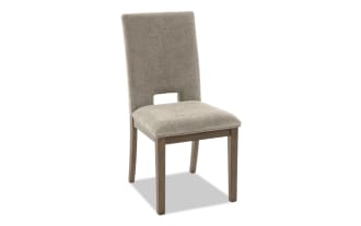 Upholstered dining chair with beige fabric seat and backrest, wooden legs, modern design, suitable for home or office seating.