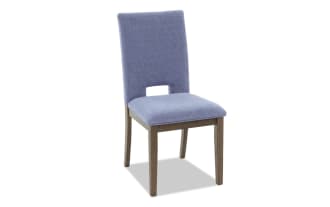 Dining chair with blue upholstered fabric seat and backrest, wooden legs, and a modern cutout design on the lower back.