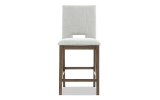 Upholstered bar stool with light gray fabric seat and backrest, wooden legs with footrest, modern dining or kitchen seating.