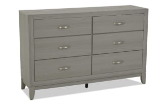 Six-drawer light gray wood dresser with brushed metal handles, modern style, rectangular frame, and sturdy legs for bedroom storage.