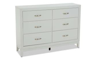 White wooden dresser with six drawers, brushed metal handles, and a modern, clean-lined design, ideal for bedroom storage.