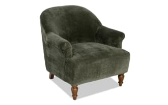 Dark green velvet armchair with rolled arms and wooden turned legs, featuring a plush, rounded back and cushioned seat for comfortable seating.