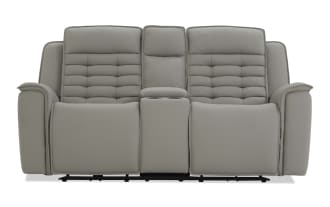 Gray leather reclining loveseat with padded armrests, tufted back cushions, and center console with cup holders, modern style.