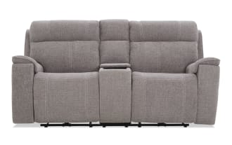 Gray fabric reclining loveseat with padded armrests, high back cushions, and a center console for storage and cup holders.