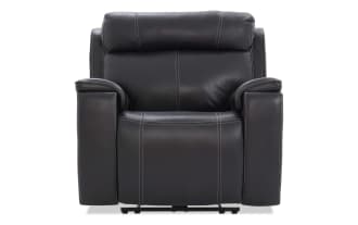 Black leather recliner chair with padded armrests, cushioned backrest, and visible white stitching, designed for comfort and modern living rooms.