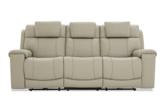 Beige leather reclining sofa with three seats, padded headrests, and cushioned armrests, designed for living room comfort and style.