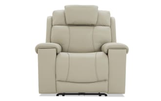 Beige leather recliner chair with padded armrests, cushioned headrest, and ergonomic stitching, designed for comfort and relaxation.