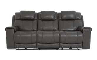 Dark gray leather reclining sofa with three seats, padded armrests, and cushioned headrests, designed for living room comfort.
