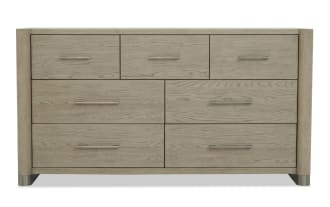 Six-drawer wooden dresser in light oak finish with modern metal handles, rounded corners, and metal-capped legs, ideal for bedroom storage.