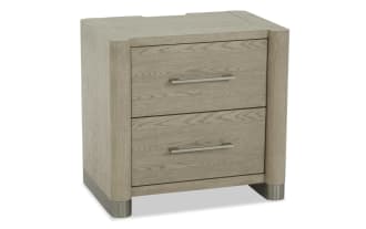 Two-drawer nightstand in light oak wood finish with brushed metal handles and rounded corners, featuring metal feet for modern bedroom storage.