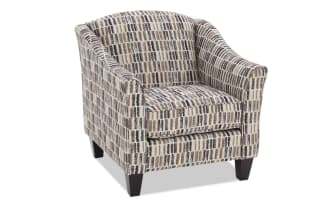 Upholstered armchair with a modern geometric pattern in beige, brown, and black tones, featuring cushioned seat and wooden legs.