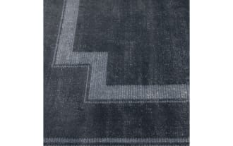 Dark blue rectangular area rug with a subtle geometric border pattern, featuring a soft, velvety texture ideal for modern home decor.
