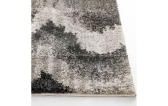 Shaggy area rug with a wavy zigzag pattern in shades of gray, black, and beige, featuring a soft, plush texture ideal for living room or bedroom decor.