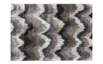 Shaggy area rug with a wavy zigzag pattern in shades of gray, black, and beige, featuring a soft, plush texture ideal for living room or bedroom decor.
