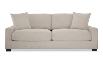 Transitional Aspen Beige 86" sofa with soft beige polyester fabric upholstery, plush cushions, accent pillows, and durable plywood frame.