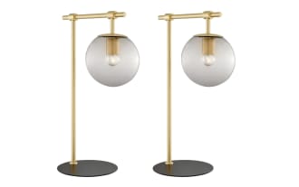 Ezra Gold Table Lamp set of 2 with transitional style, nickel frame, black base, and clear glass globe shade showcasing ambient bulbs for warm lighting.
