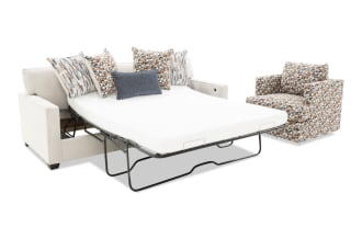 Beige fabric sofa bed with metal frame and patterned cushions, paired with a multicolor patterned swivel armchair, showcasing modern living room furniture.