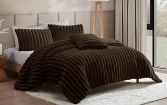 Dark brown plush ribbed bedding set on a modern bed with matching pillows, featuring a soft textured comforter and decorative cushion.