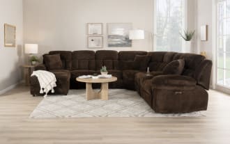 Brown plush fabric sectional sofa with chaise lounge, two matching cushions, and padded armrests, designed for living room comfort.